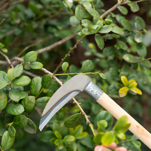 Hoz de jardín con mango de madera.